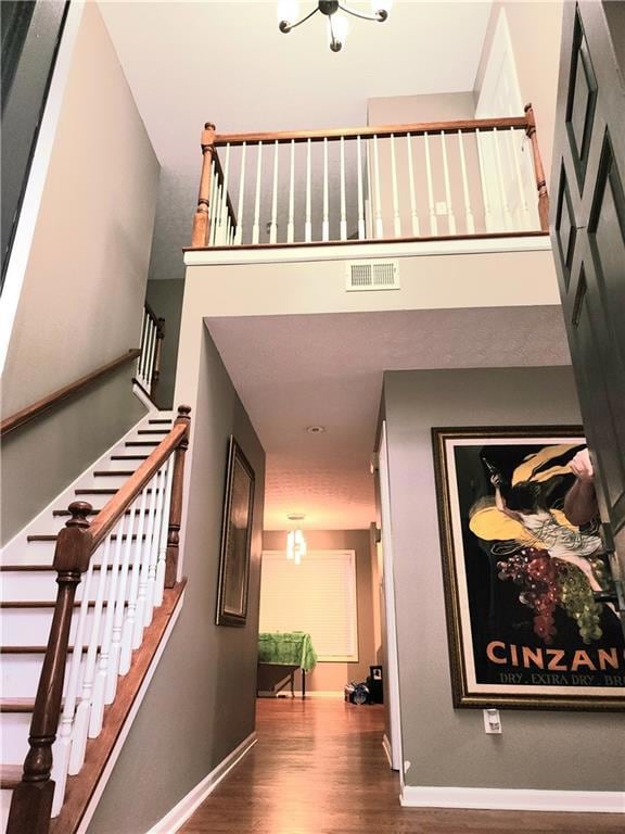 Stairs with wood finished floors and a chandelier