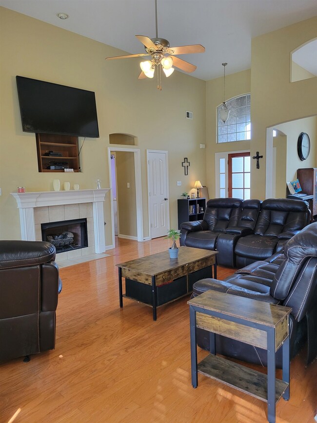 Living room featuring ceiling fan, a fireplace, li