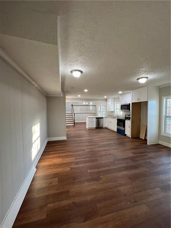 Unfurnished living room featuring a textured ceiling, dark wood finished floors, baseboards, and recessed lighting