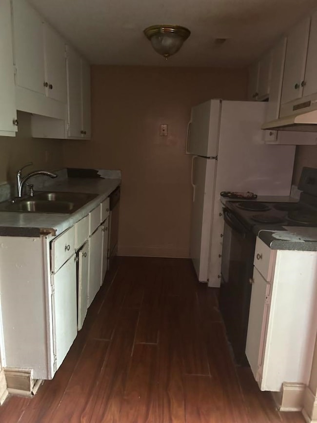 Kitchen featuring black / electric stove, under cabinet range hood, dark wood-style flooring, and white cabinets