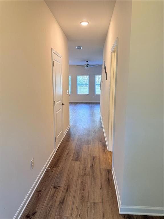 Hall with dark wood-type flooring and baseboards