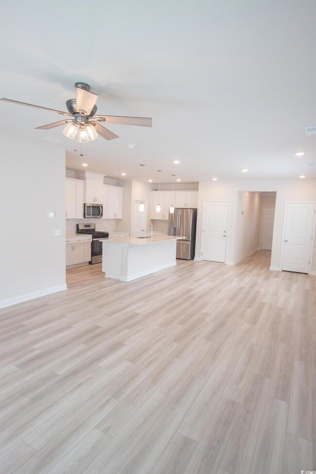 Unfurnished living room with baseboards, a sink, a ceiling fan, light wood finished floors, and recessed lighting