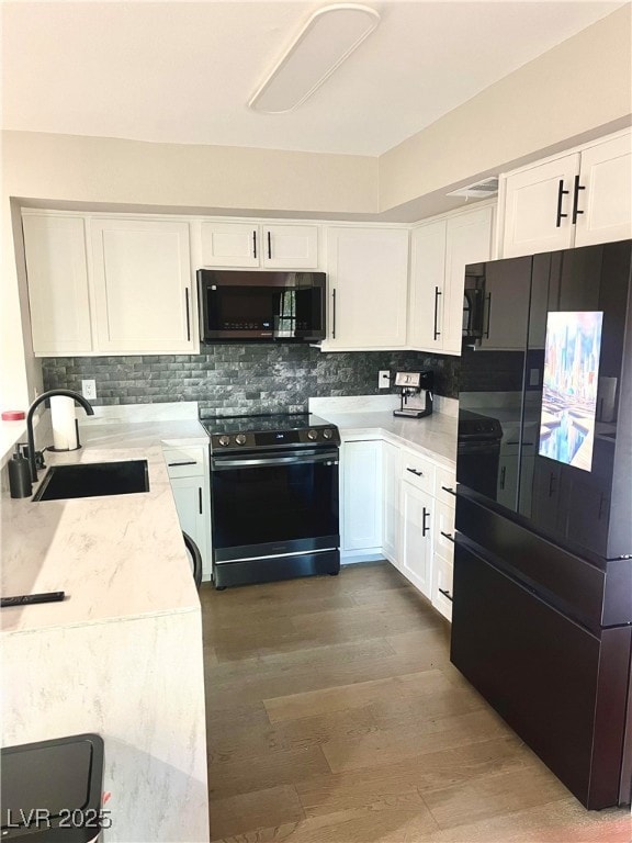 Kitchen with white cabinetry, black fridge, decora