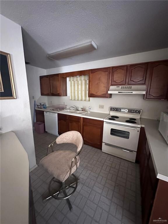 Kitchen with a textured ceiling, sink, and white appliances