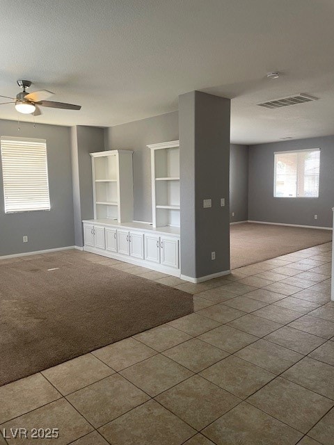 Carpeted spare room featuring ceiling fan, baseboa