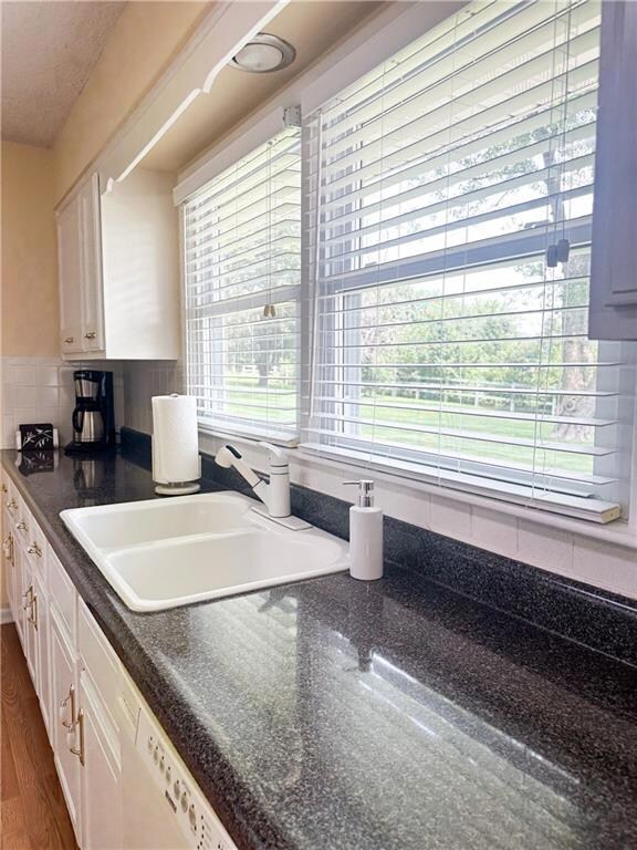 Kitchen featuring white cabinets, dishwasher, a textured ceiling, tasteful backsplash, and dark wood-type flooring