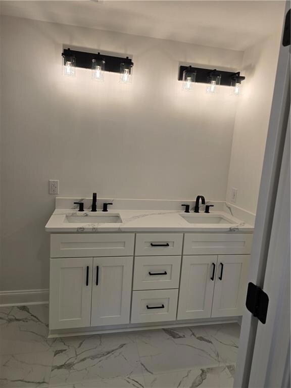 Full bath featuring light marble finish floors and a sink