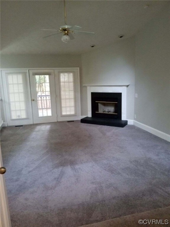 Unfurnished living room with dark colored carpet and ceiling fan