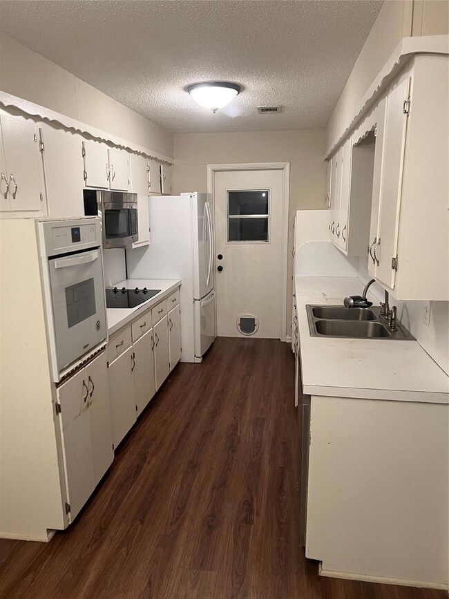 Kitchen featuring cooktop, sink, white cabinetry, 