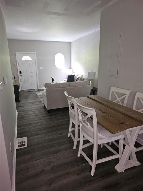 Dining area featuring electric panel and dark wood-style floors