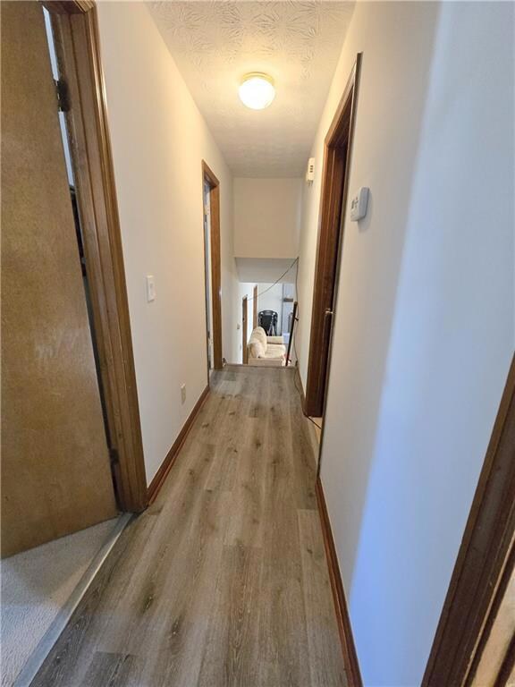 Hall featuring a textured ceiling and light wood-t