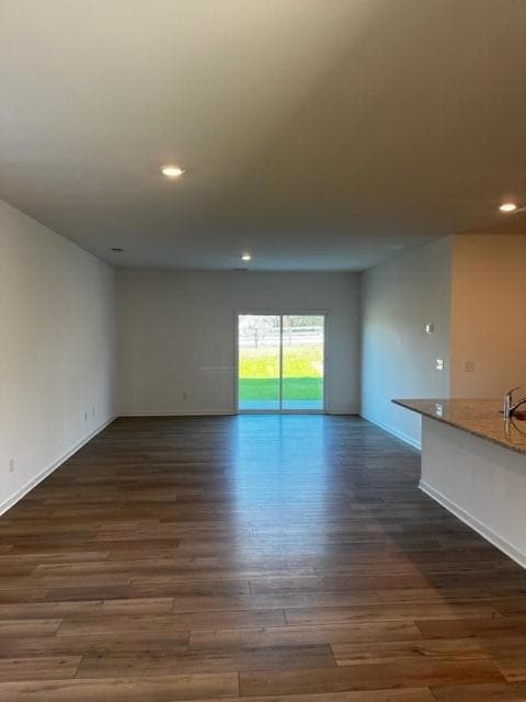 Unfurnished living room featuring recessed lighting and dark wood-style flooring