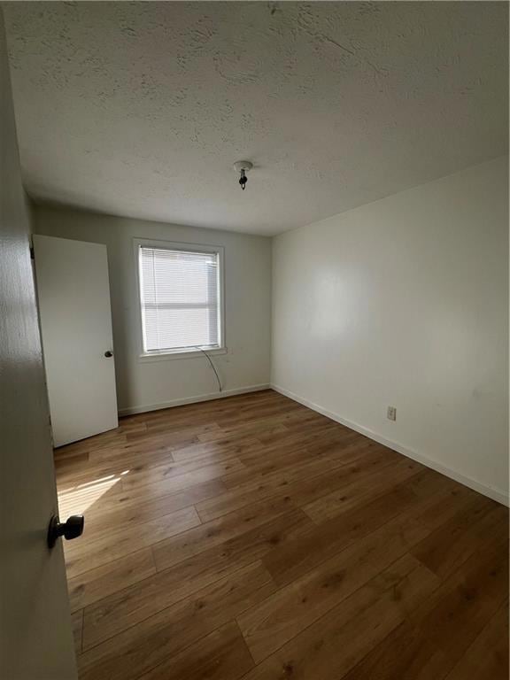 Empty room featuring light hardwood / wood-style floors and a textured ceiling