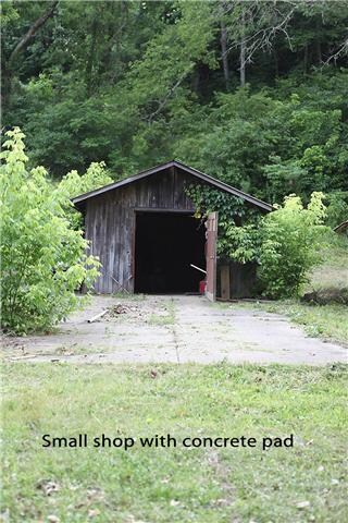 Small shop with concrete pad out front of it.