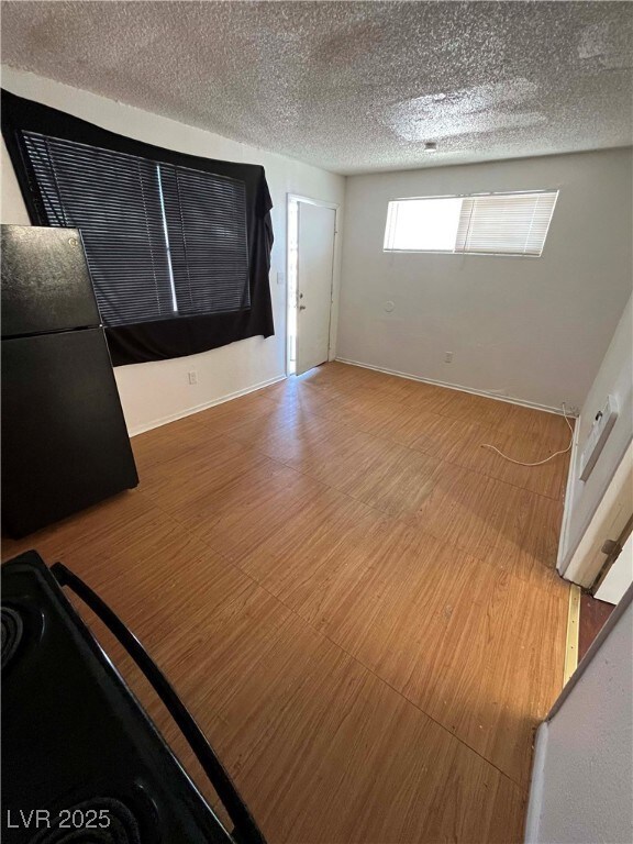 Unfurnished room featuring a textured ceiling, woo