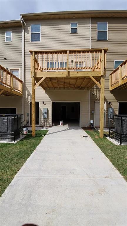 Back of house with a patio, concrete driveway, a deck, and an attached garage