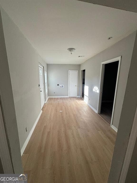 Hallway with light wood-type flooring and baseboards