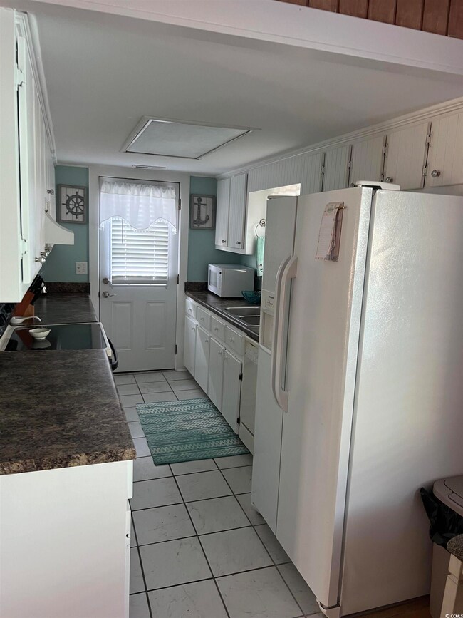 Kitchen featuring white cabinets, light tile patte