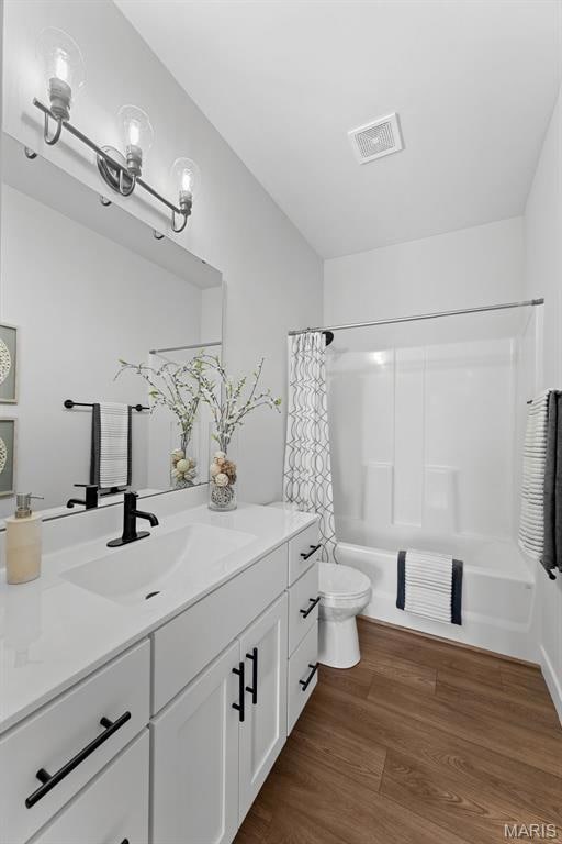 Bathroom featuring shower / tub combo with curtain, dark wood-style flooring, and vanity