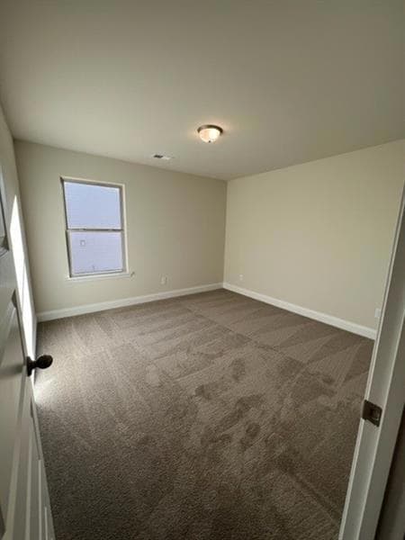 Spare room with dark colored carpet and baseboards