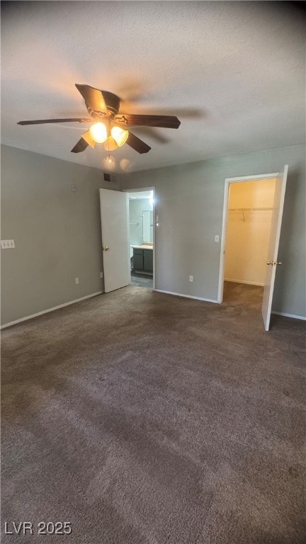 Carpeted empty room with a ceiling fan and baseboa