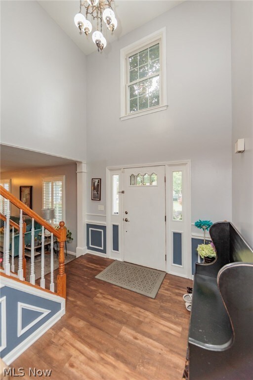 Entrance foyer featuring a healthy amount of sunlight, high vaulted ceiling, wood-type flooring, and a chandelier