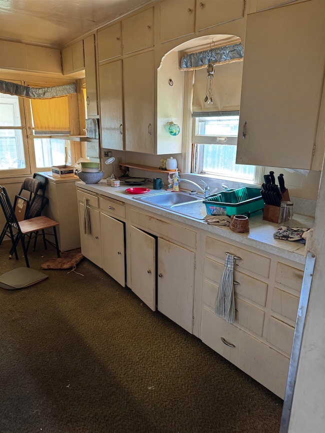 Kitchen with light countertops, dark colored carpet, and washer / clothes dryer