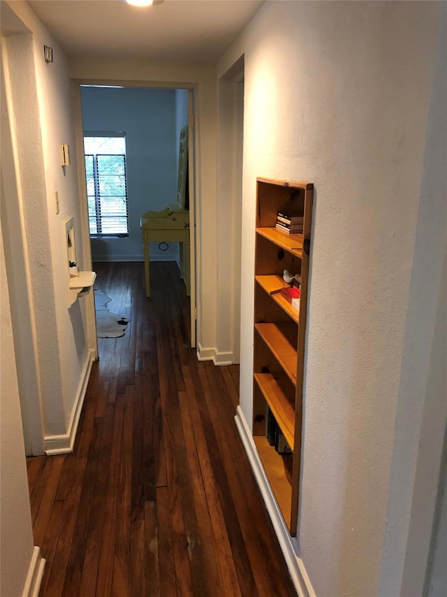 Hallway with wood-type flooring and baseboards