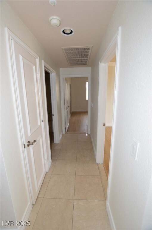 Hallway with light tile patterned floors, visible