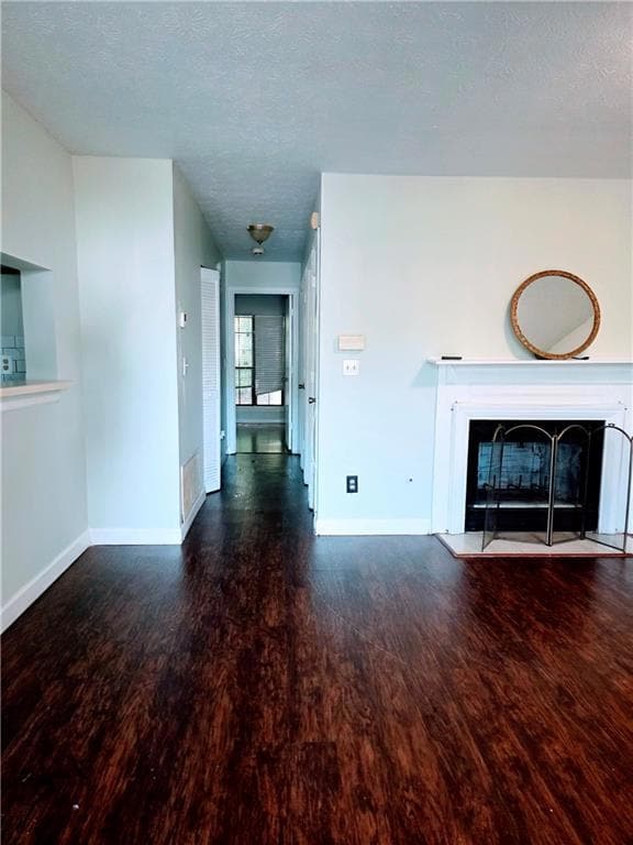 Unfurnished living room featuring a textured ceiling, dark wood-type flooring, and a fireplace