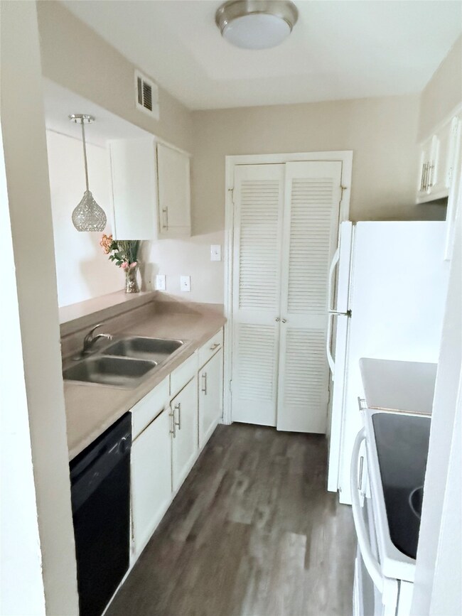 Kitchen with white cabinetry, white appliances, includes fridge, hanging light fixture, with in-unit laundry room
