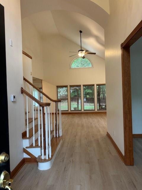 Foyer entrance with a ceiling fan, wood finished floors, arched walkways, stairway, and baseboards