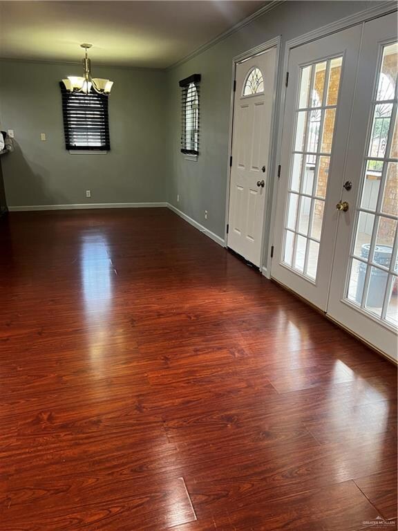 Foyer entrance with an inviting chandelier, dark wood-style floors, and a wealth of natural light