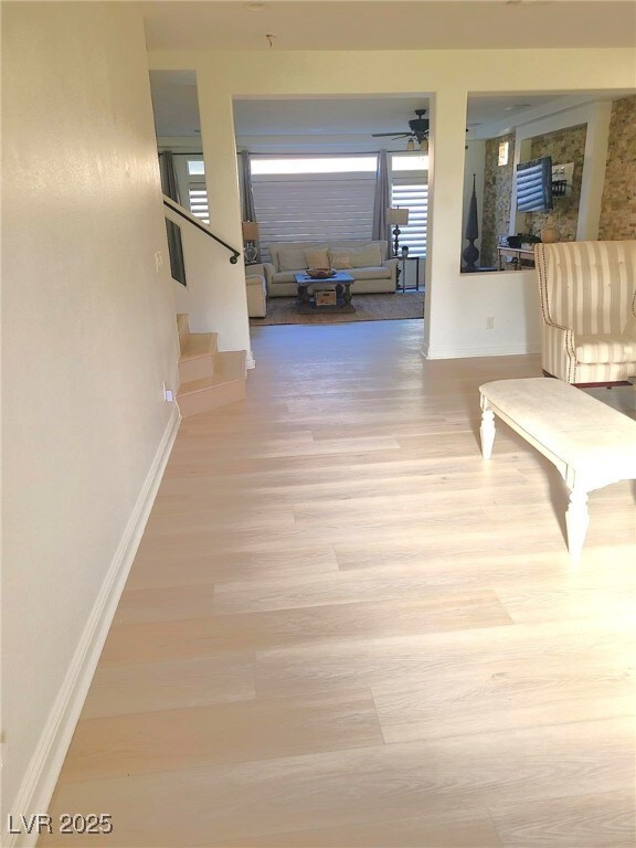 Hall featuring baseboards, stairway, and wood fini