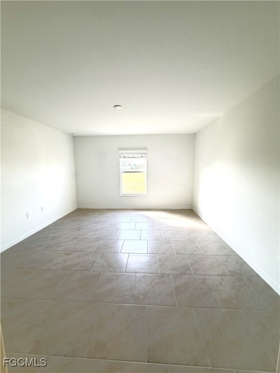 Spare room with baseboards and light tile patterned flooring