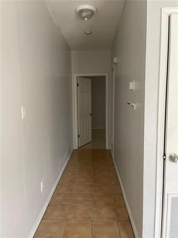 Hallway featuring light tile patterned floors and baseboards