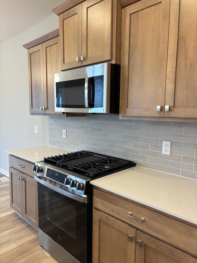 Gas slide in range, quartz countertops, beautiful backsplash grace the kitchen