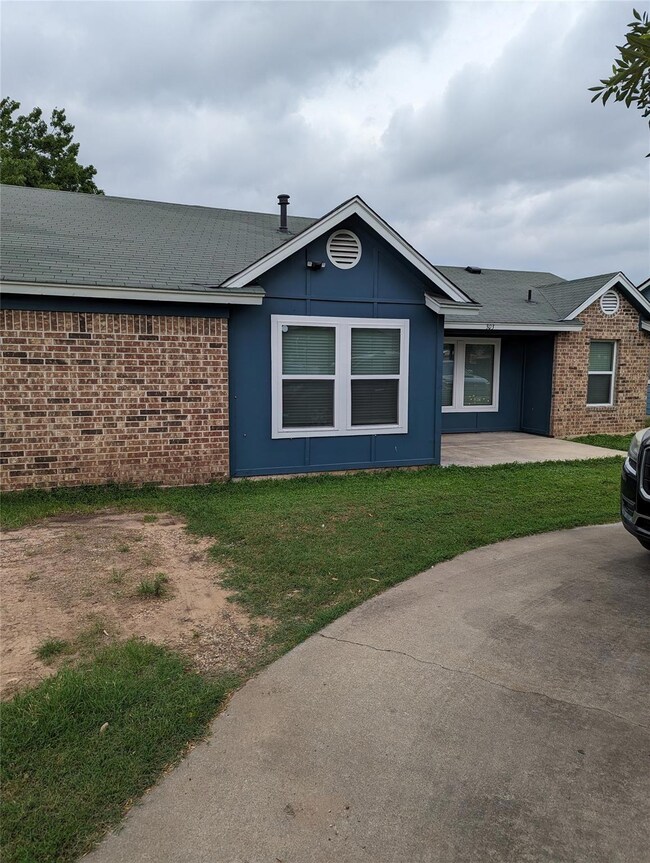 View of property exterior with a yard, brick sidi