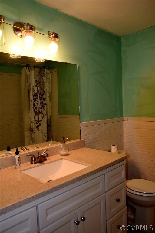 Bathroom featuring backsplash, tile walls, toilet,