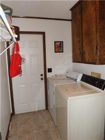 The large utility room features overhead cabinets and shelves and has a door leading to the back yard.