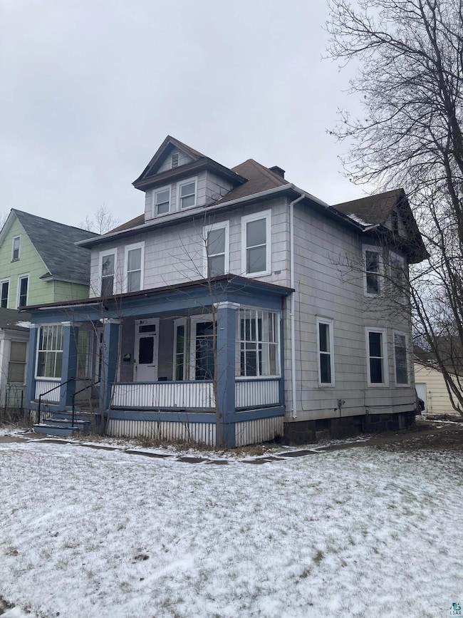 Snow covered rear of property featuring a porch