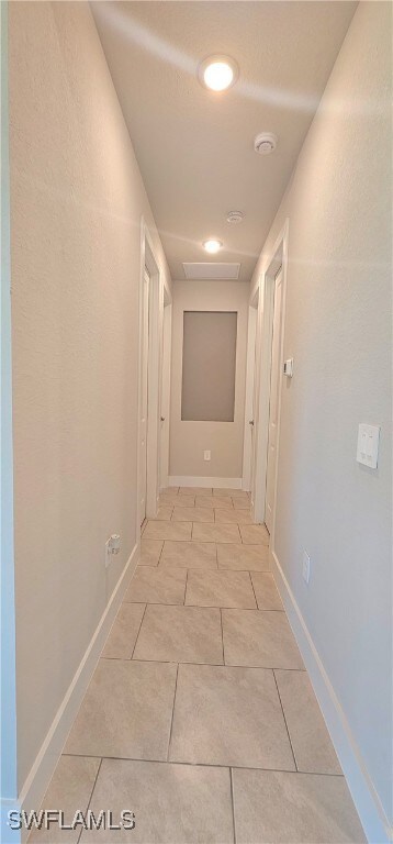 Hallway featuring light tile patterned floors, bas