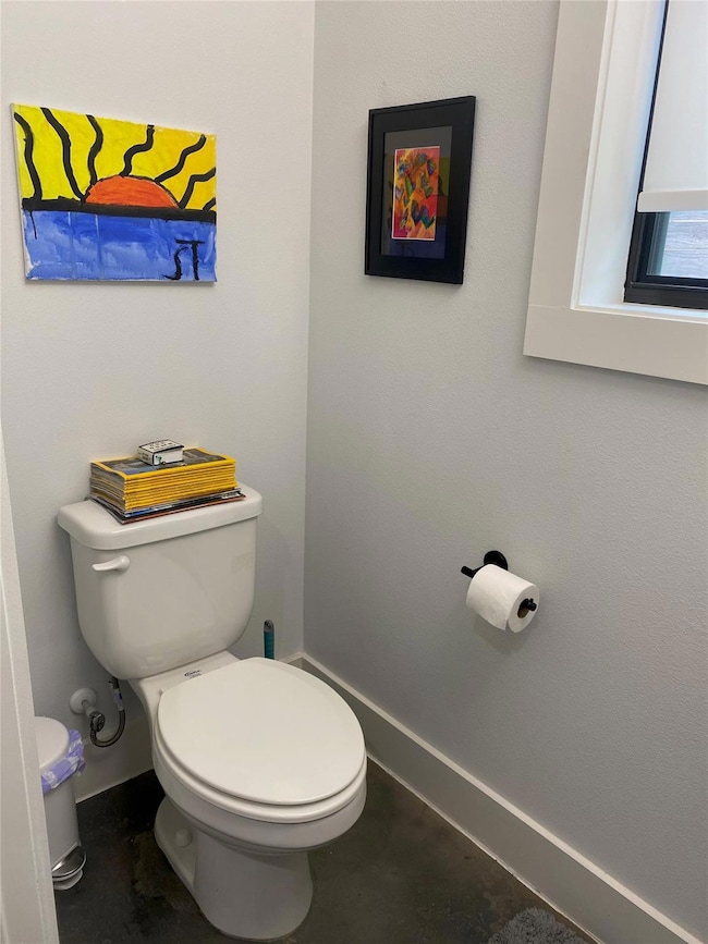 Bathroom with toilet and concrete floors