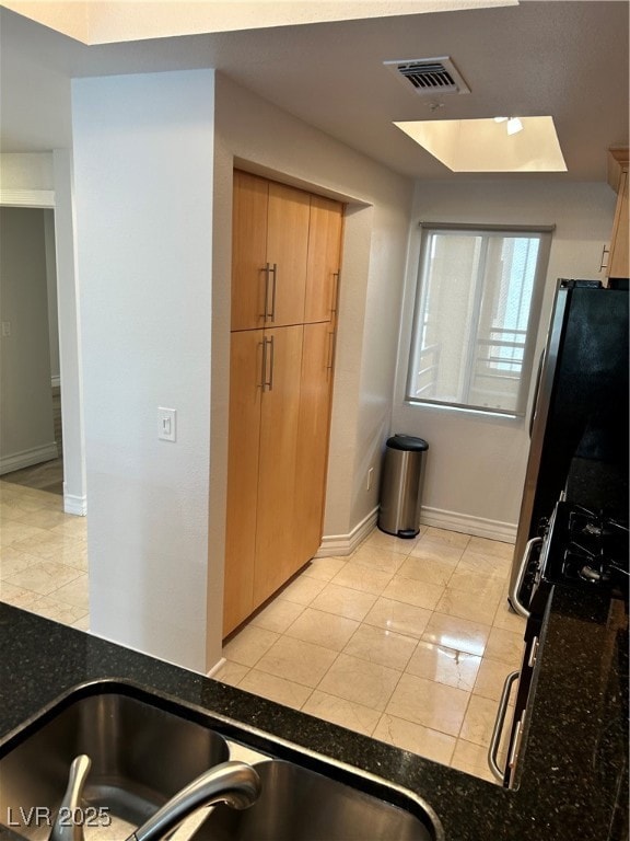 Kitchen with baseboards and dark stone counters
