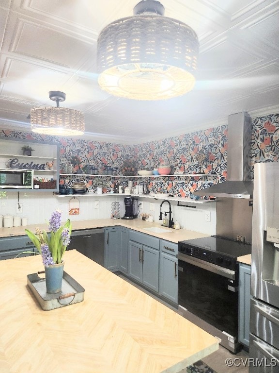 Kitchen featuring appliances with stainless steel finishes, wall chimney exhaust hood, light countertops, open shelves, and crown molding