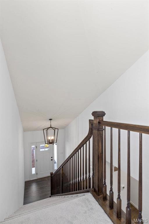 Stairway with hardwood / wood-style floors and an inviting chandelier