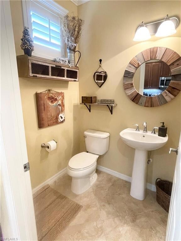 Half bathroom with baseboards and toilet