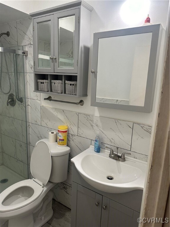 Bathroom with tile walls, a tile shower, vanity, a