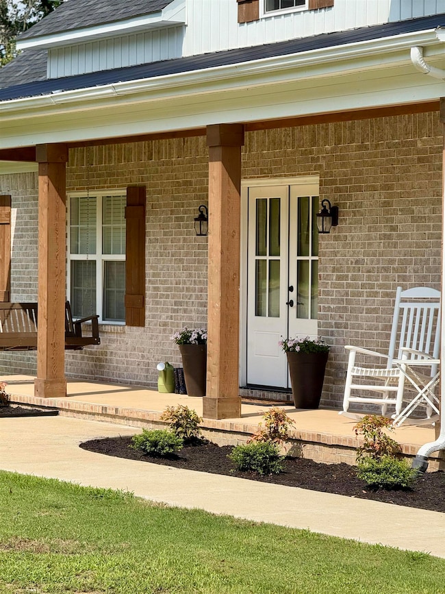 View of exterior entry featuring brick siding and a porch