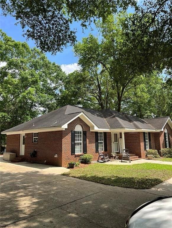 Single story home featuring brick siding, concrete driveway, and a front lawn